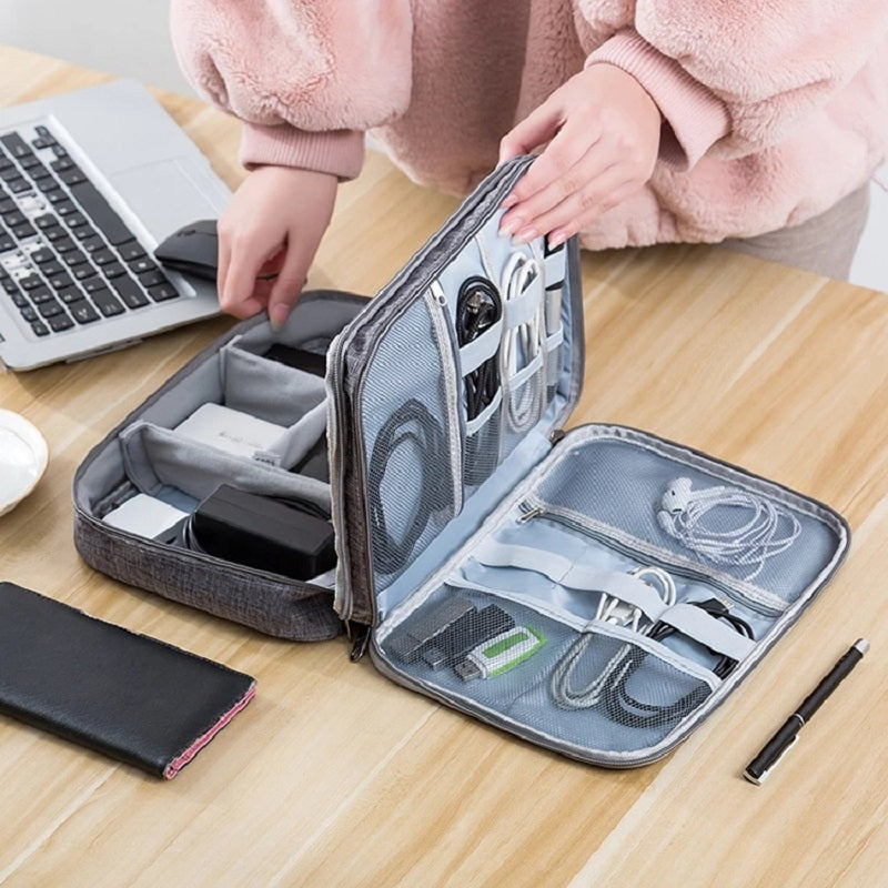 Gray travel organizer with electronic items on a wooden table