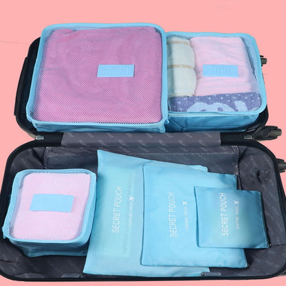 Set of travel packing cubes in pink and blue with 'Secret Pouch' branding on a pink background.