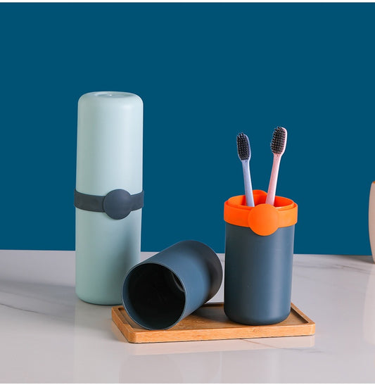 Set of bathroom accessories including a green toothbrush container, and a blue  toothbrush holder on a wooden tray with a blue background.