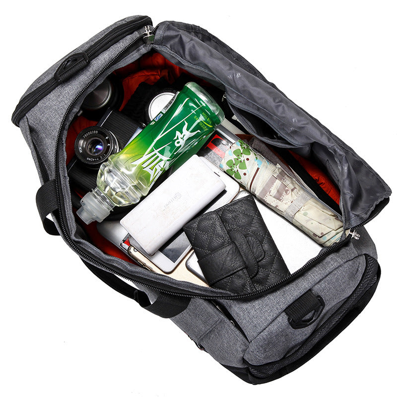 Gray duffle weekender bag with various items inside including a bottle, camera, and books on a white background
