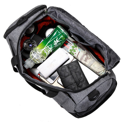 Gray duffle weekender bag with various items inside including a bottle, camera, and books on a white background