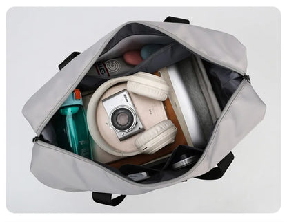 Gray weekender duffle bag with item including a camera, water bottle, and headphones inside.