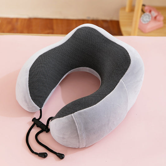 Gray neck pillow on a pink surface with a blurred background
