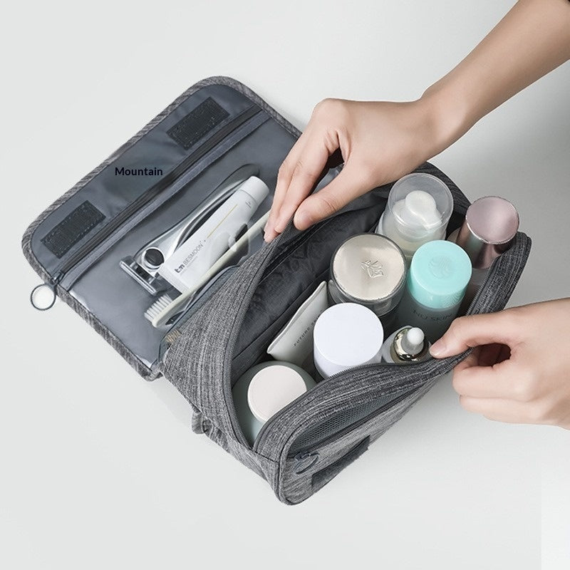Gray toiletry bag with various travel-sized products on a light gray background