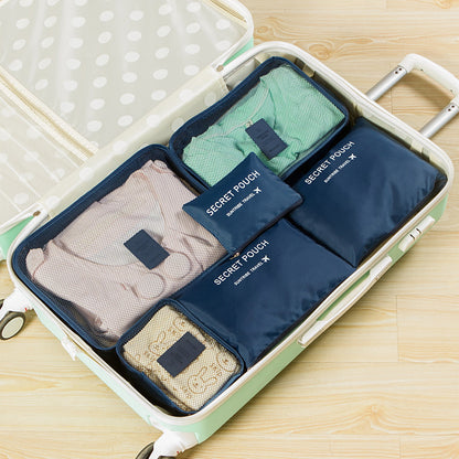 Set of navy blue packing cubes labeled 'Secret Pouch' inside an open suitcase on a wooden surface.