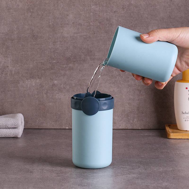 Person pouring water from a blue container into another blue container on a gray surface.