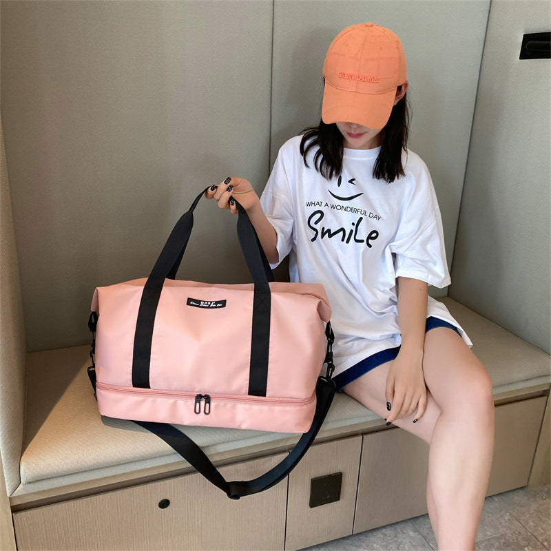 Person holding a pink duffel bag by its black straps with a white shirt and orange cap indoors.